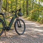 Parked e-bike and helmet beside a wooded trail.